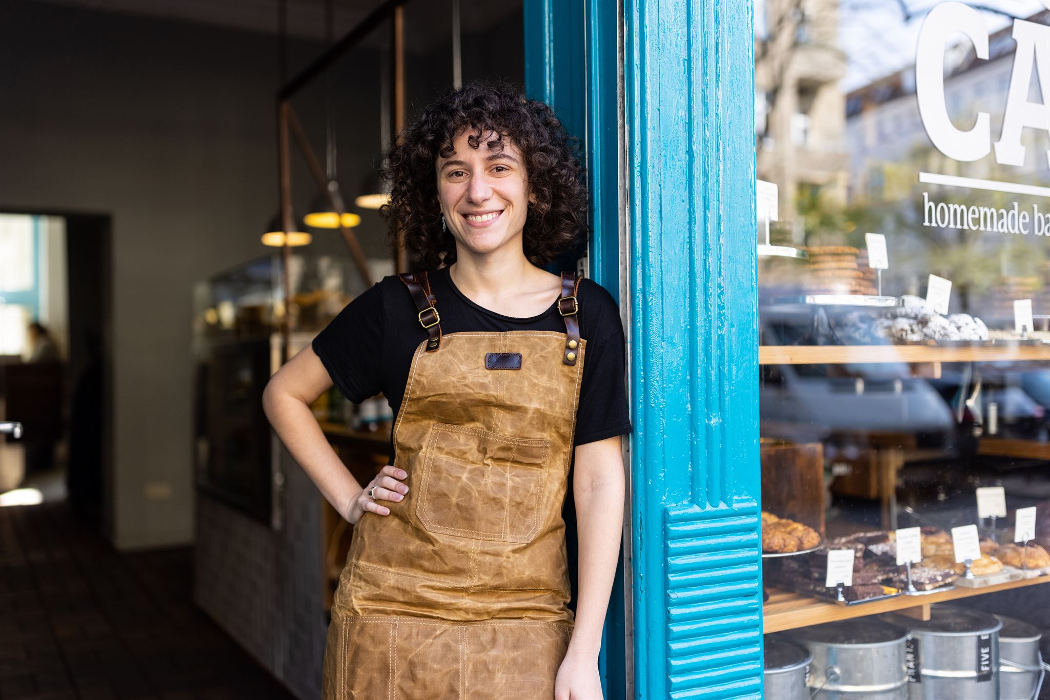 Person-in-apron-standing-outside-bakery